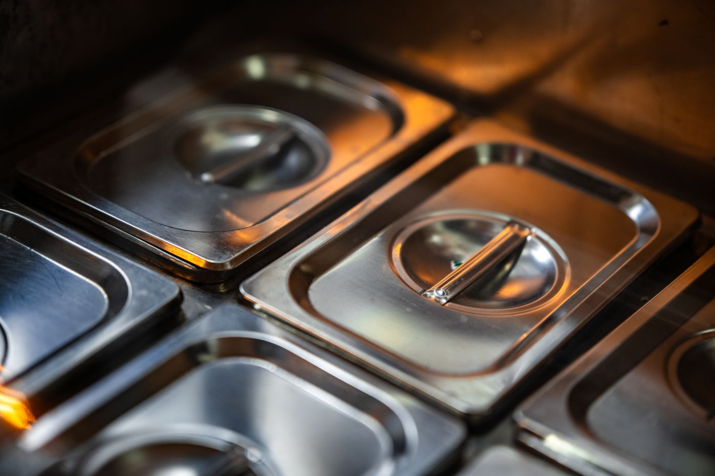 Covered stainless containers on a shelf in a restaurant kitchen, the kind of stock a count sheet has to account for
